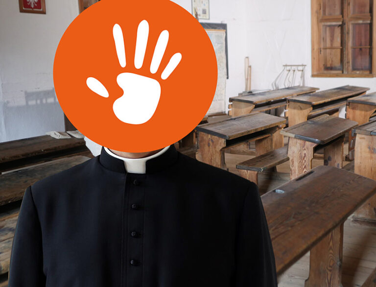 ksiądz w klasie szkolnej z łapką fundacji na twarzy